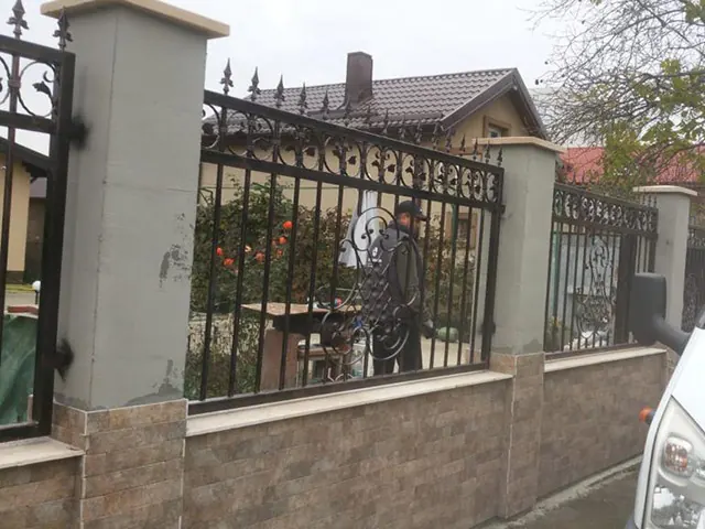 Gard din fier forjat cu sulițe între stâlpi de zidărie