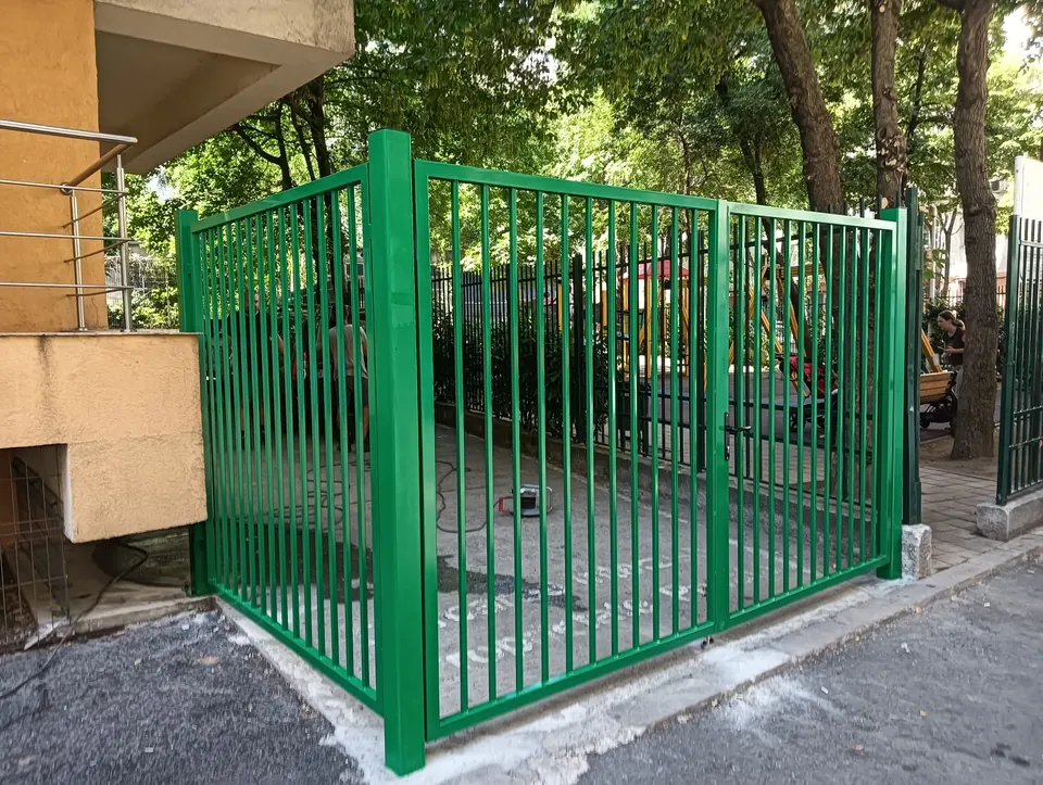 Împrejmuire verde cu bare verticale și porți